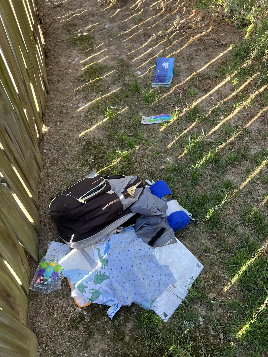 Backpack and bedding piled by a wood fence