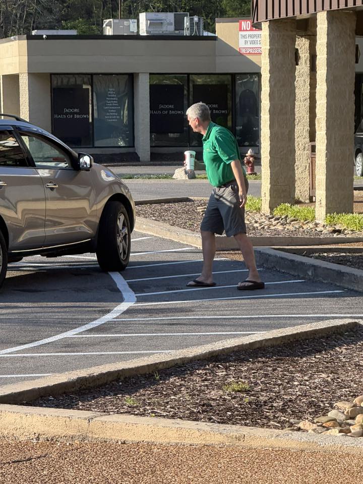 Man in green polo crossing parking lot